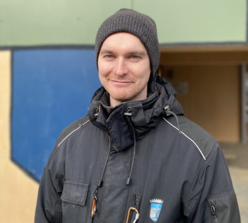 Smilende mannlig barnehageansatt i kommunal jakke
