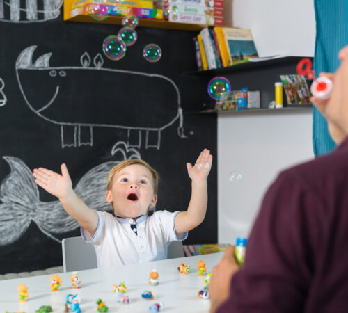 Mannlig barnehagelærer blåser bobler med barn