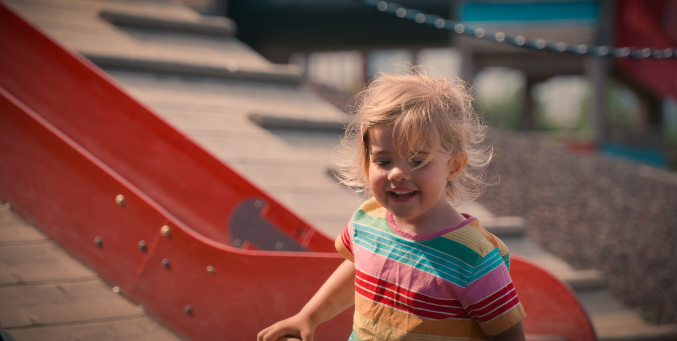 Smilende jente foran en rød sklie