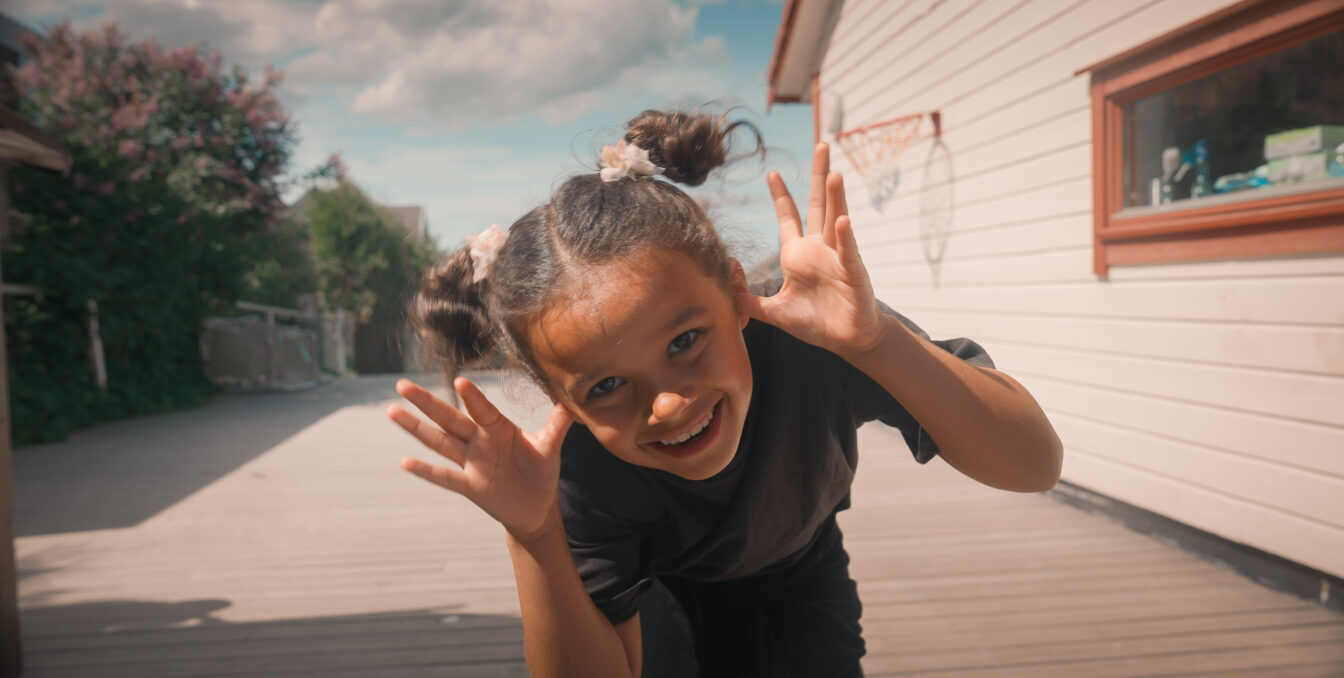 Jentebarn tøyser og smiler foran kameraet
