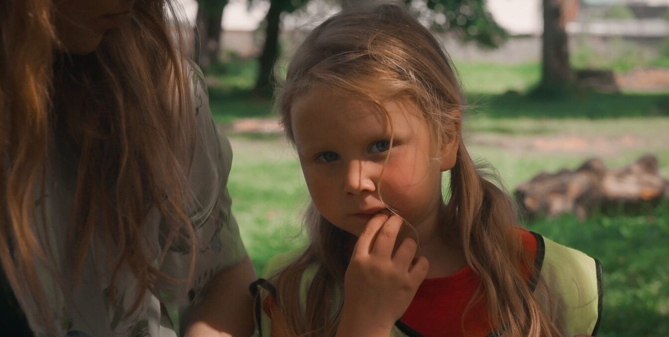 En jente ser undrende inn i kameraet mens hun spiser lunsj.