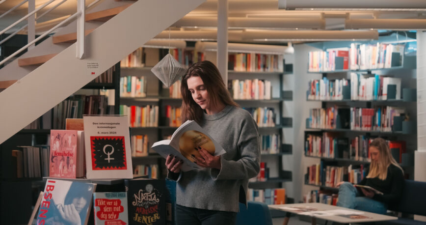 Student leser bok i biblioteket