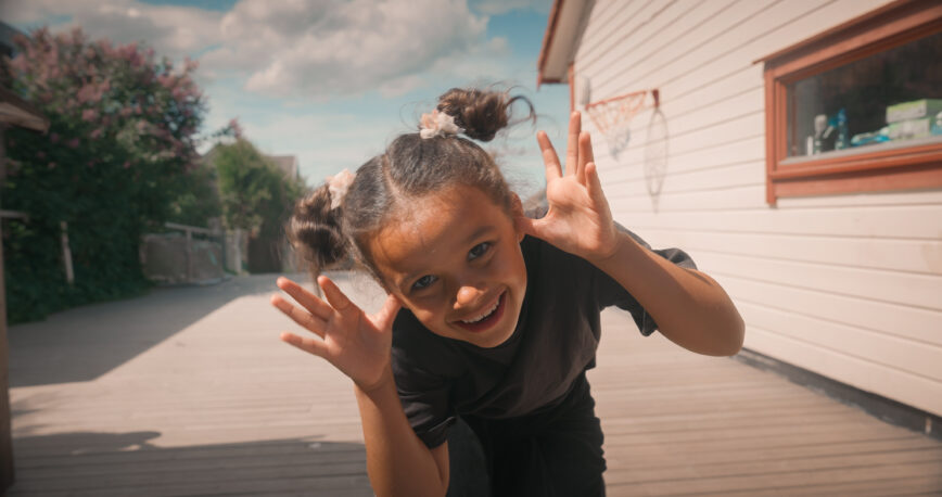 Jentebarn tøyser og smiler foran kameraet