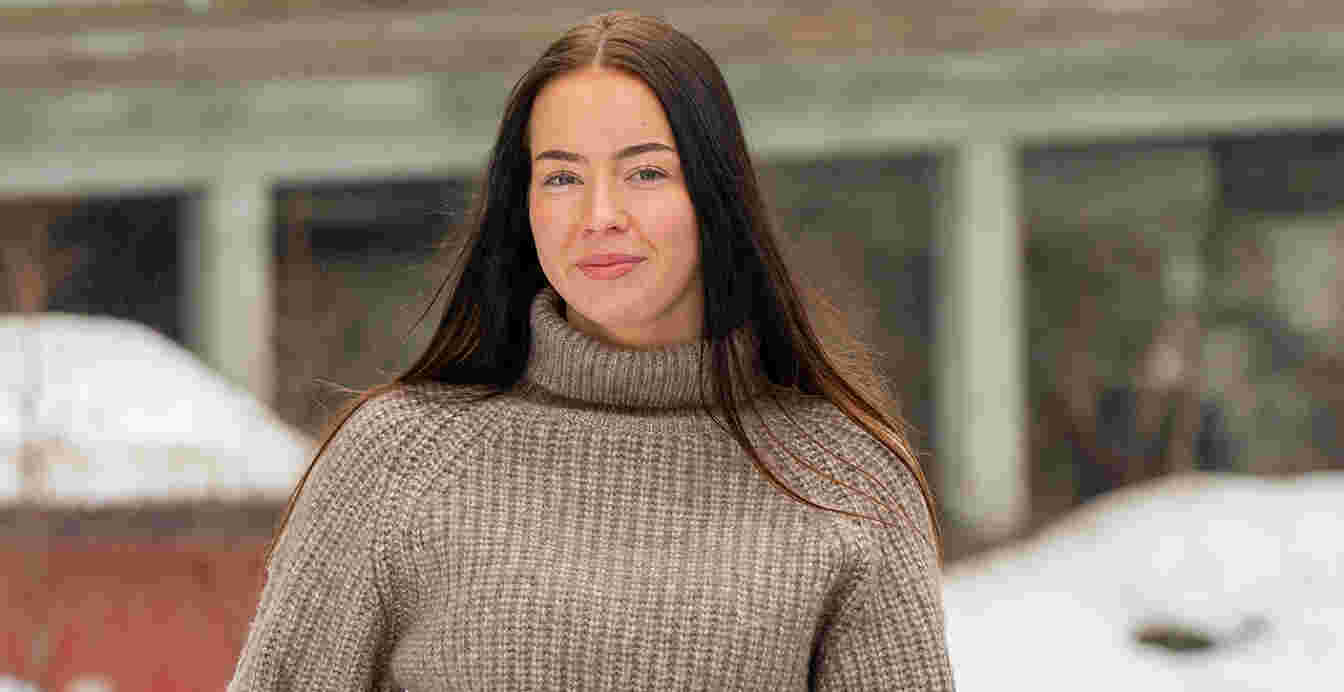 Kvinnelig student ser mot kamera på en snøfylt dag