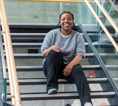 Smilende kvinnelig student sittende i en trapp