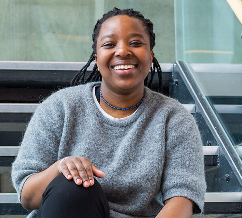 Smilende student sittende i ei trapp