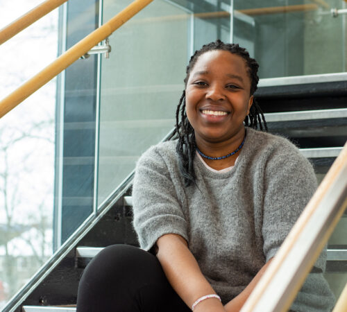Smilende kvinnelig student sittende i ei trapp