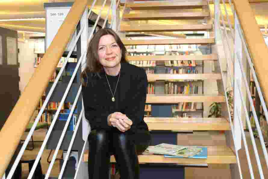 Dette er et bilde av dosent Cecilie Dyrkorn Fodstad som sitter i en trapp i høgskolens bibliotek.
