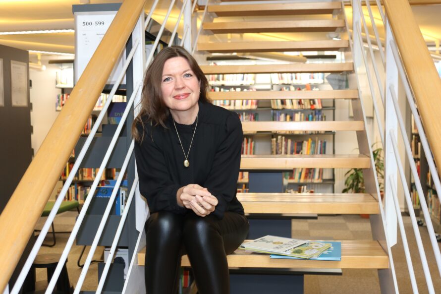 Dette er et bilde av dosent Cecilie Dyrkorn Fodstad som sitter i en trapp i høgskolens bibliotek.