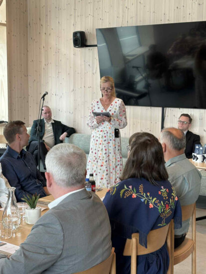 En kvinne snakker til en pyntet forsamling.