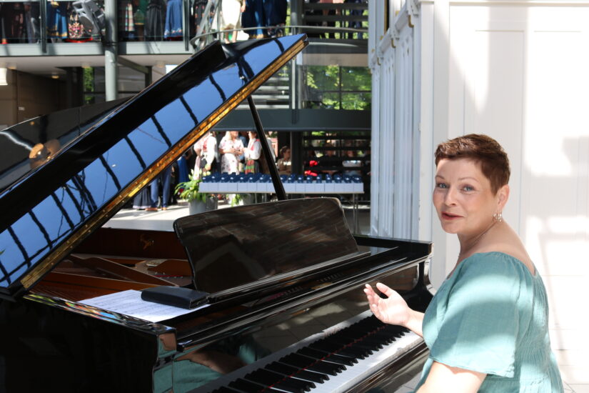 En kvinne i fin kjole sitter ved et flygel.