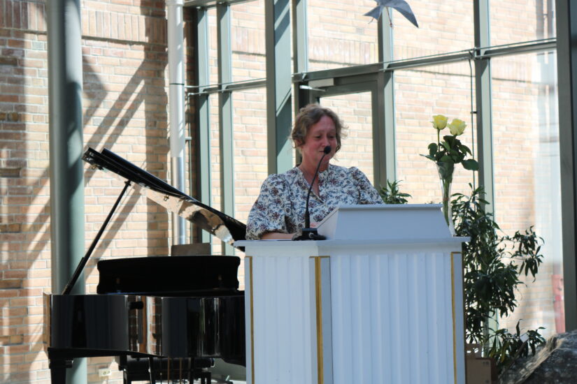 En kvinne i pen kjole står på en talerstol.