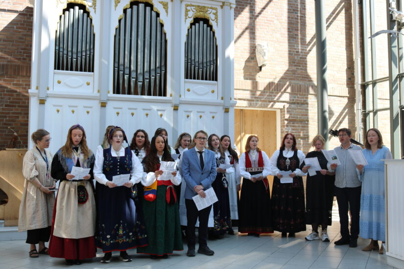 Festkledte unge mennesker synger inne på DMMH.