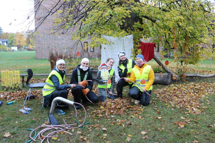 Noen ungdommer sitter utendørs med gule vester på.