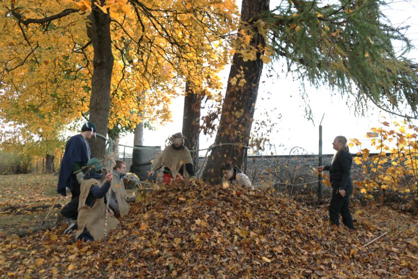 Flere utkledde ungdommer sitter i en løvhaug.
