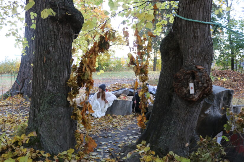 To kvinner er avbildet bak to trær.