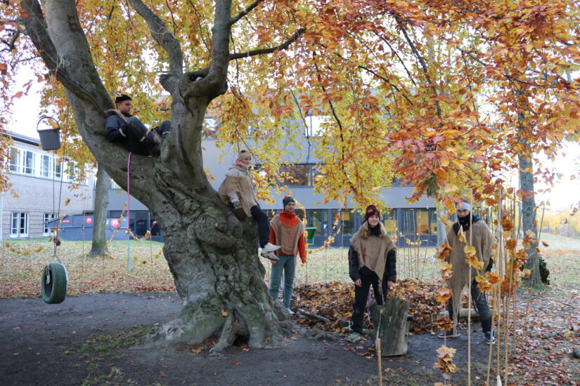 En person ligger i et tre mens flere andre står på bakken.