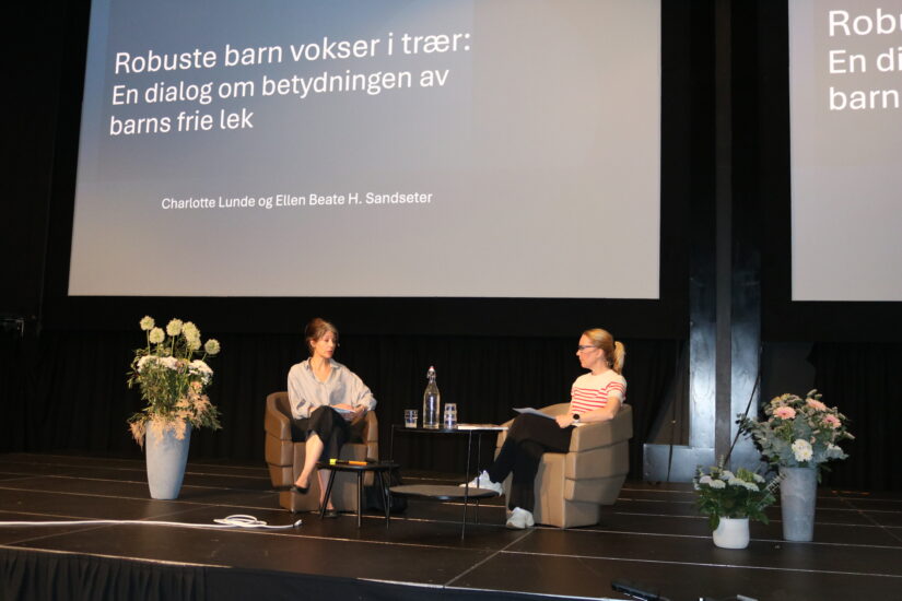 To kvinner sitter i samtale oppe på en scene