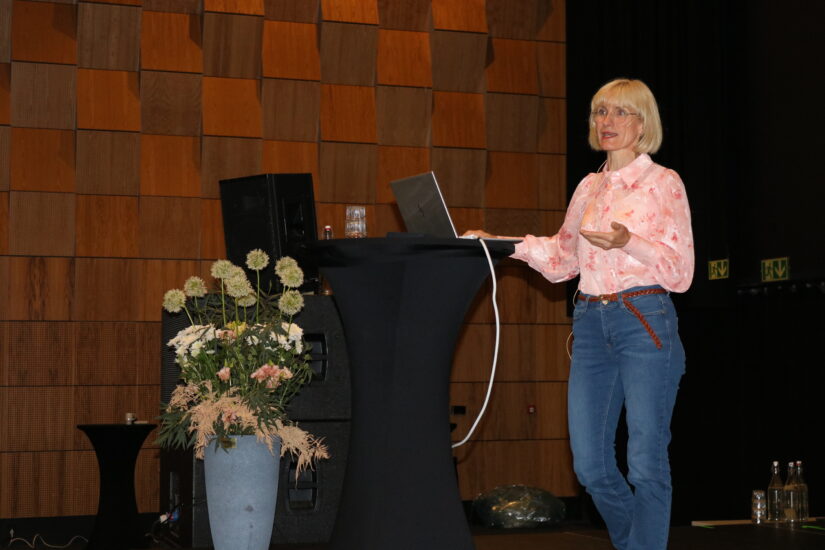 En kvinne står ved en talerstol og taler.