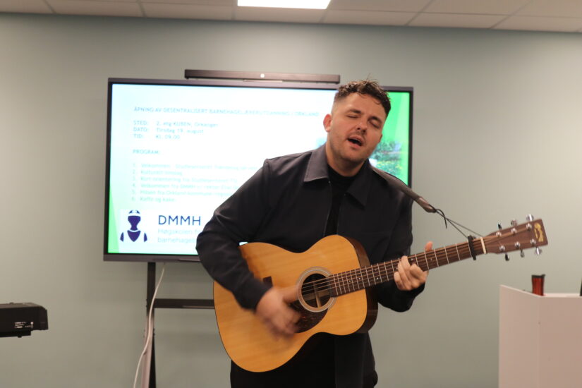 En mann med gitar synger.