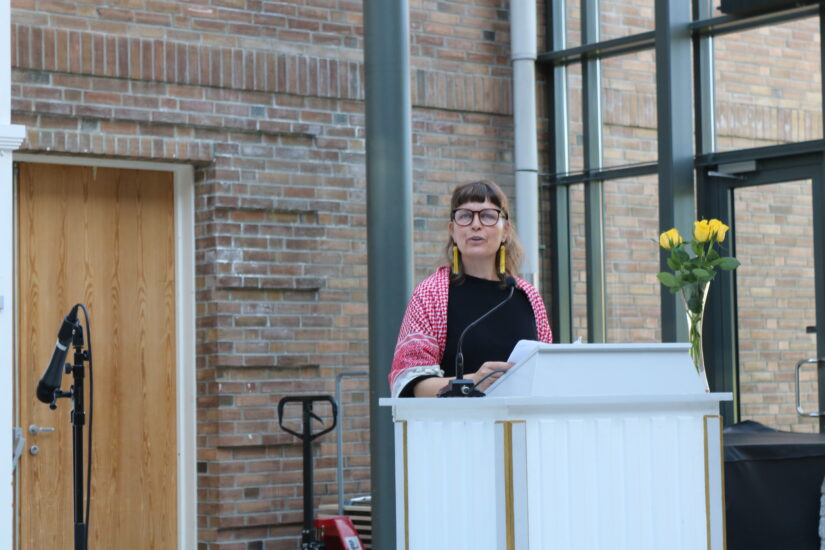 En kvinne iført Palestinaskjerf står på en talerstol.