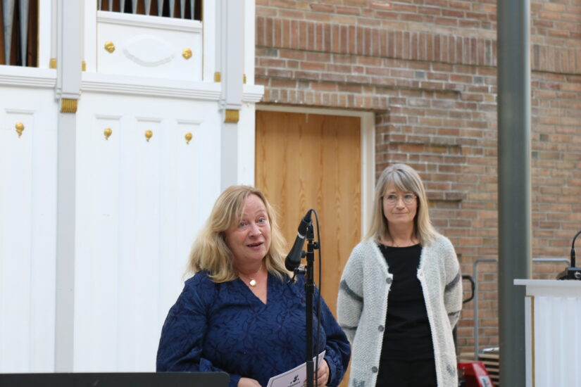 To kvinner står ved et mikrofonstativ.