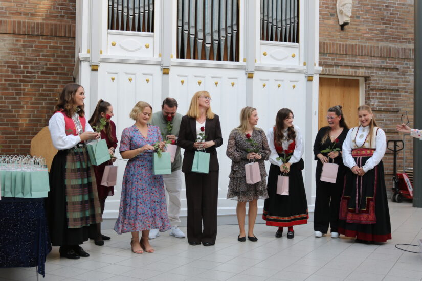 Mennesker som er pent pyntet står foran et orgel.