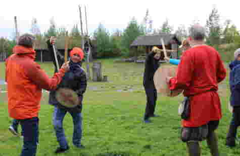 Flere menn slår mot hverandre med tresverd og skjold.