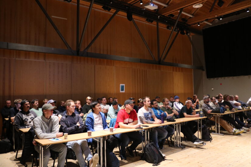 Mange menn sitter samlet som i et klasserom.