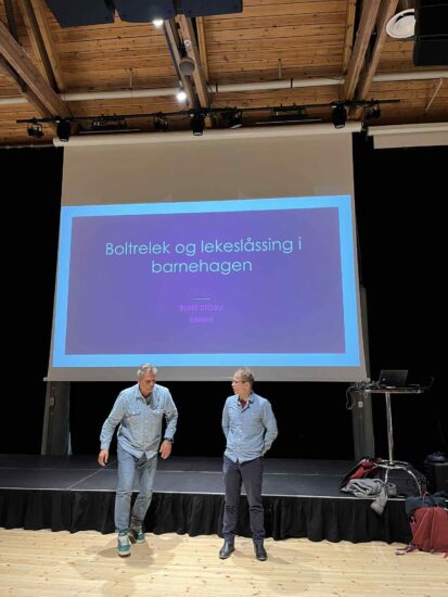 To menn i like skjorter står på en scene sammen.