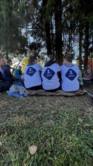 En gjeng ungdommer sitter med ryggen til i skogen.