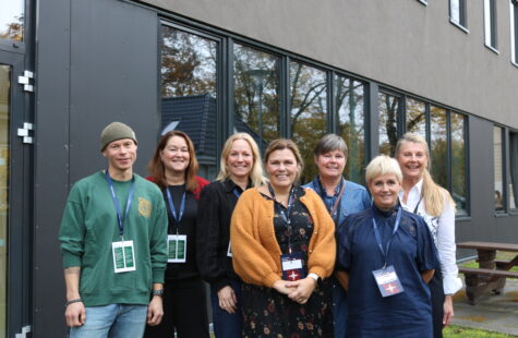 En gruppe mennesker fotografert foran en stor vegg.