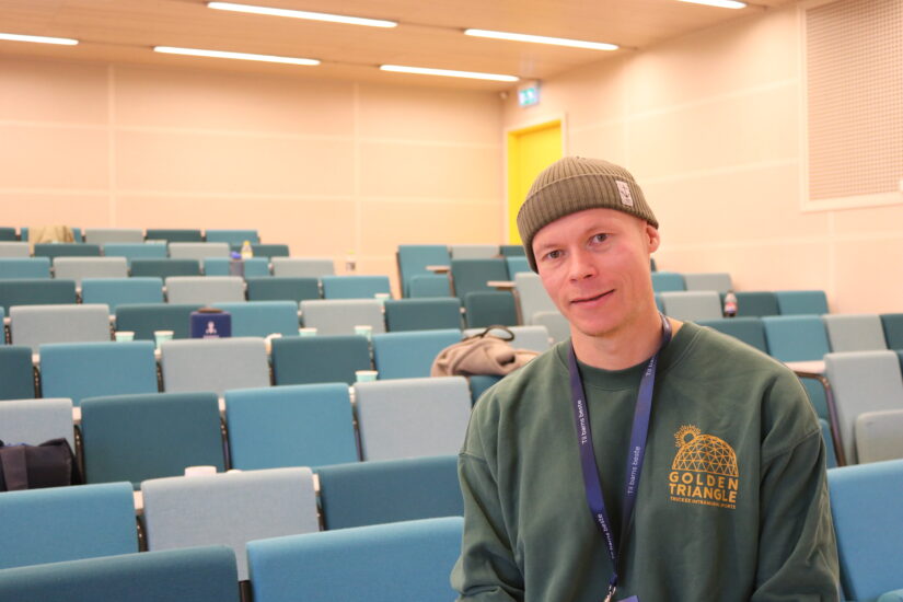 En mann står foran mange stoler i et auditorium.