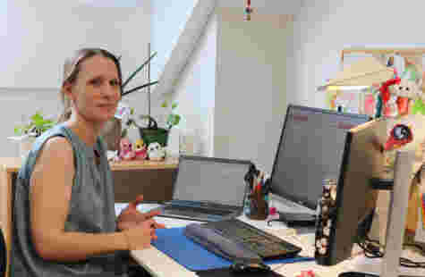 En kvinne sitter foran en pc-skjerm ved et skrivebord.