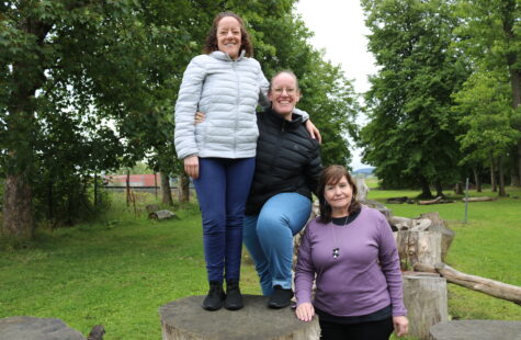 Three kvinner står oppe på trestubber.