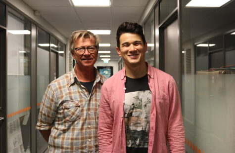 To menn sår smilende i en korridor.