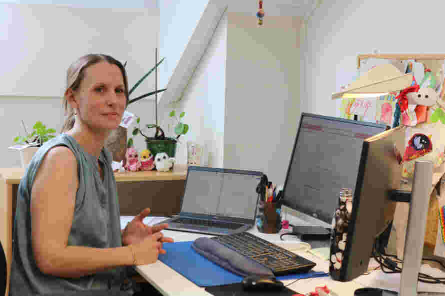 En kvinne sitter foran en pc-skjerm ved et skrivebord.