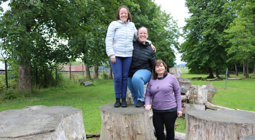 3 kvinner står delvis oppå noen trestubber