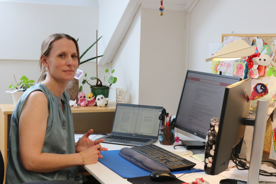 En kvinne sitter foran en pc-skjerm ved et skrivebord.