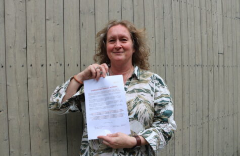 DMMH undertegner intensjonsavtale med Studiesenteret Romsdal En kvinne står foran en vegg og holder opp et ark med skrift.