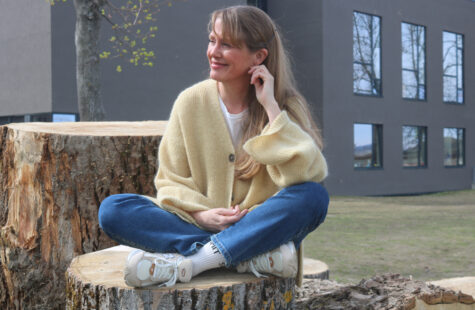 En kvinne sitter på en trestubbe.