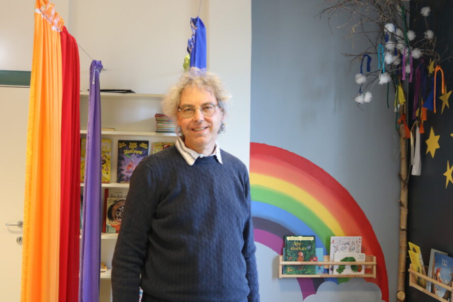 En mann står i et rom med regnbuefarger rundt seg.