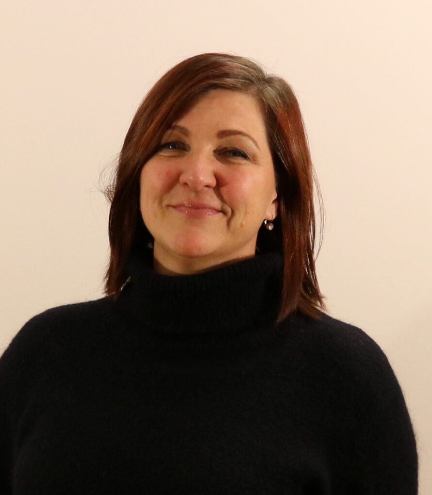 Portrait of a dark haired woman dressed in a dark sweater.