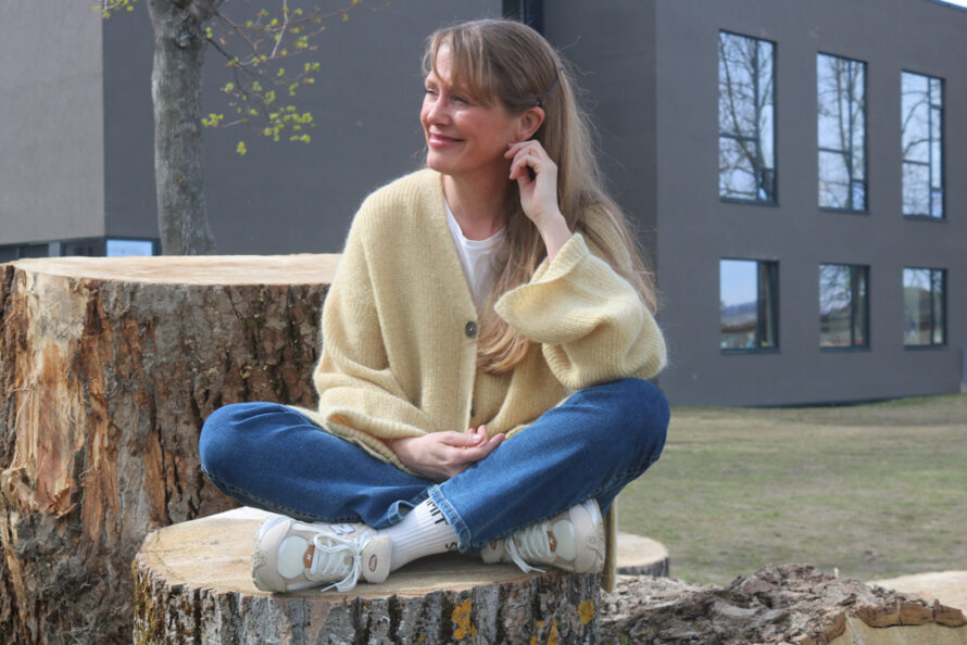 En kvinne sitter på en trestubbe.