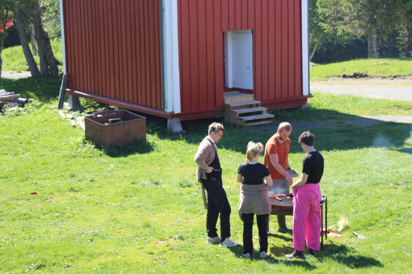 Oversiktsbilde av 4 personer som står samlet rundt en grill.