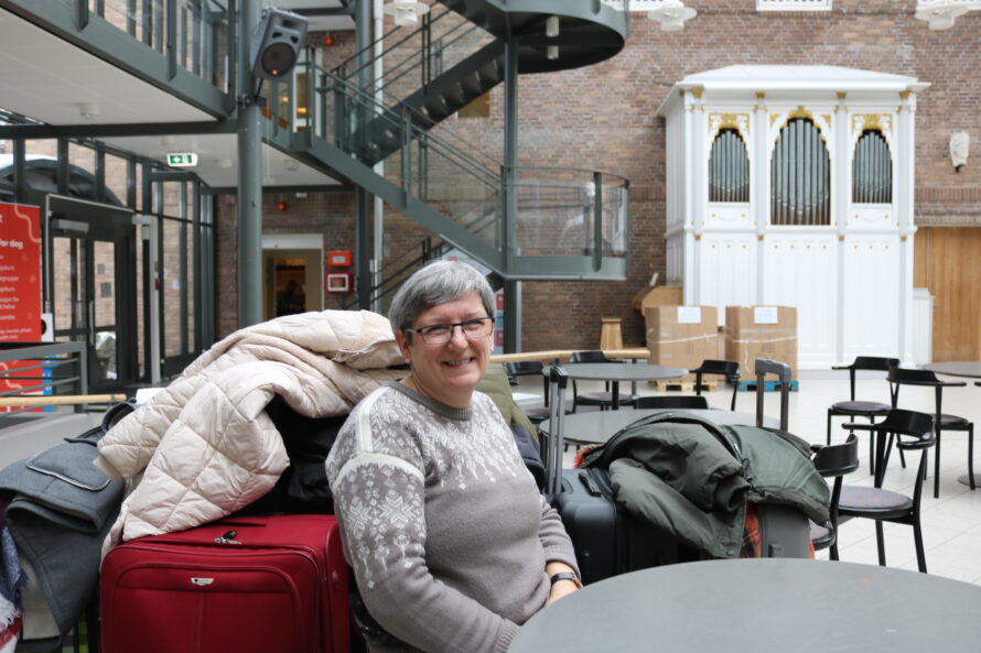 Portrett av en dame som sitter foran noen kofferter.