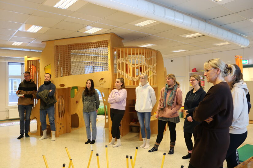 Some adults are in a room with some playing apparatus.