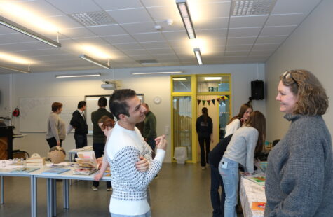 En ung mann og en kvinne har en hyggelig diskusjon. I bakgrunnen er det flere mennesker.