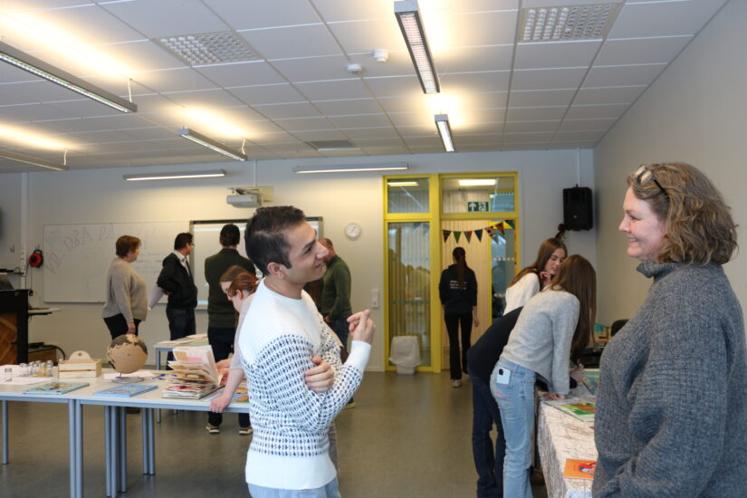 En ung mann og en kvinne har en hyggelig diskusjon. I bakgrunnen er det flere mennesker.