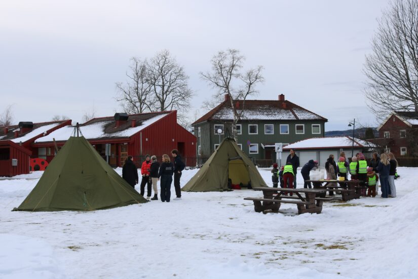 To lavvoer står plassert i snøen, med en del folk i nærheten.